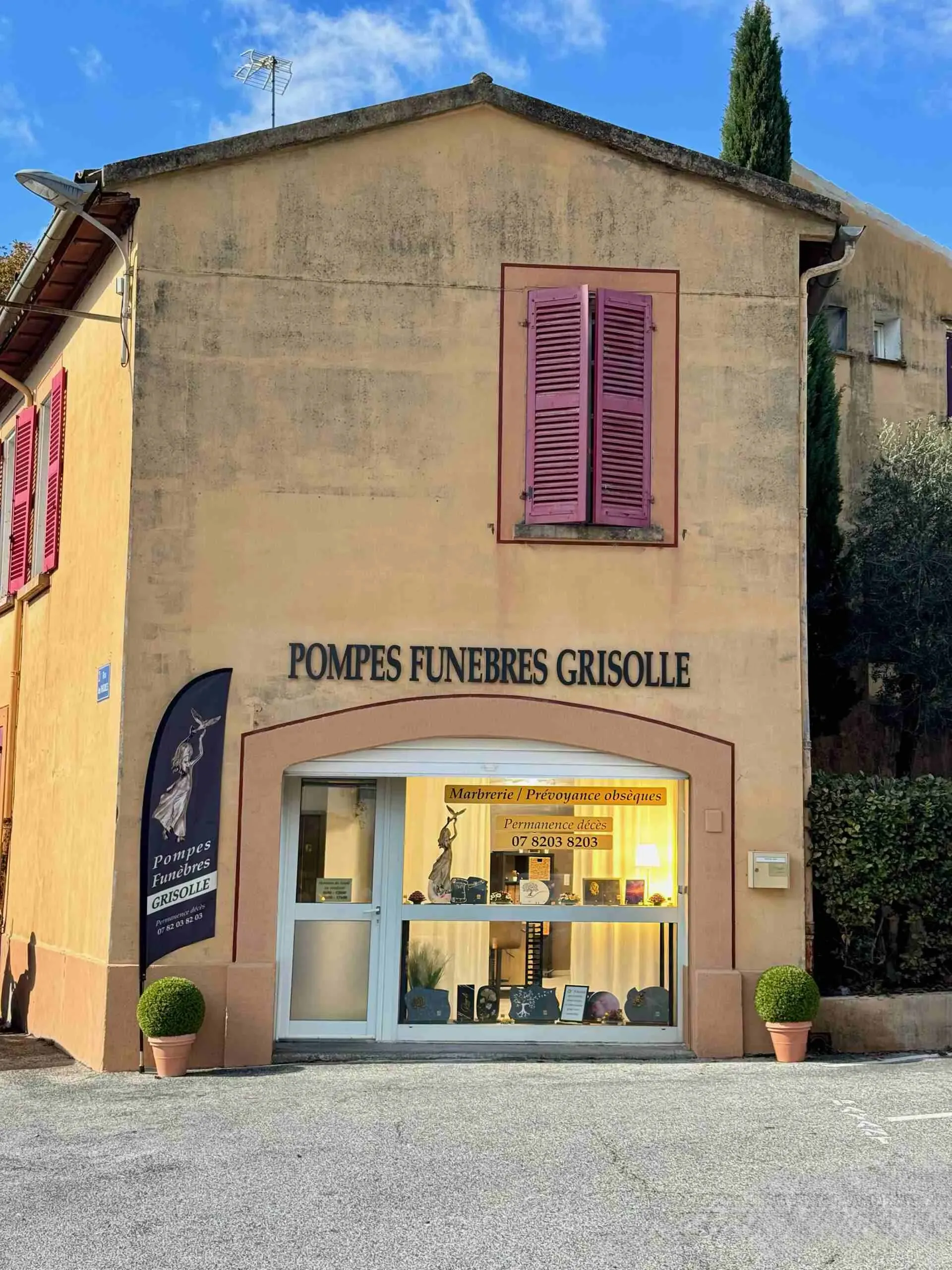 Façade de l'agence de pompes funèbres Grisolle avec sa vitrine éclairée.