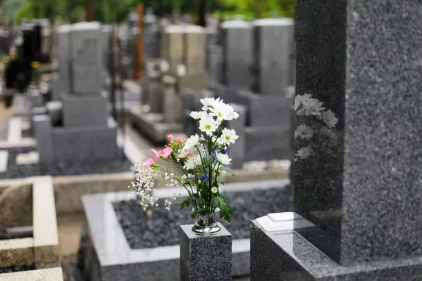 Fleurs blanches déposées près d'une pierre tombale dans un cimetière.
