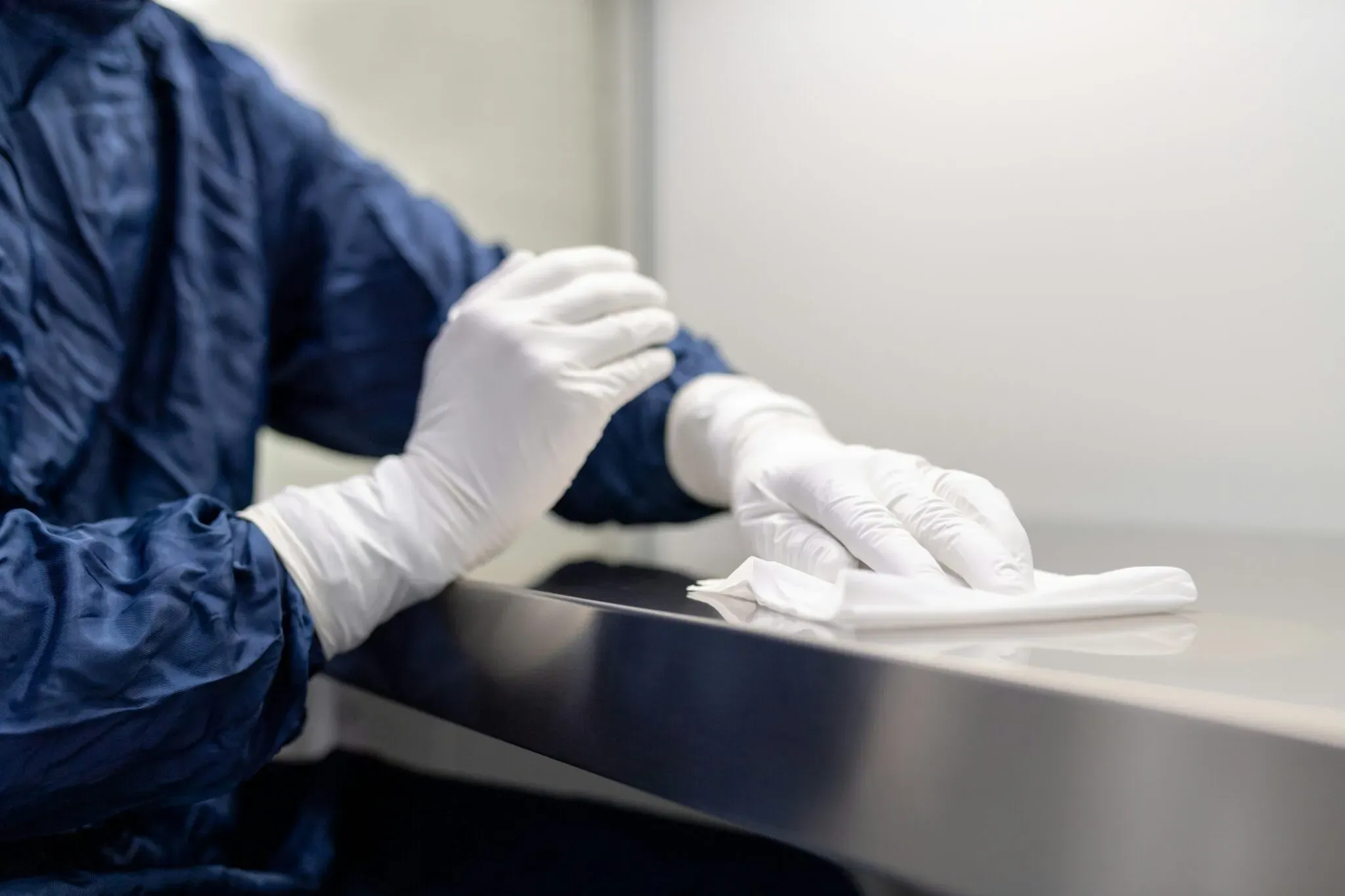 Désinfection minutieuse d'une surface métallique par une personne en tenue médicale.